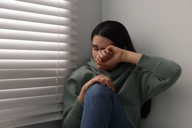 Photo of Sadness. Unhappy woman crying near window at home