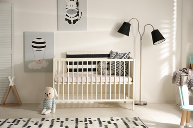 Photo of Cute baby room interior with crib and decor elements