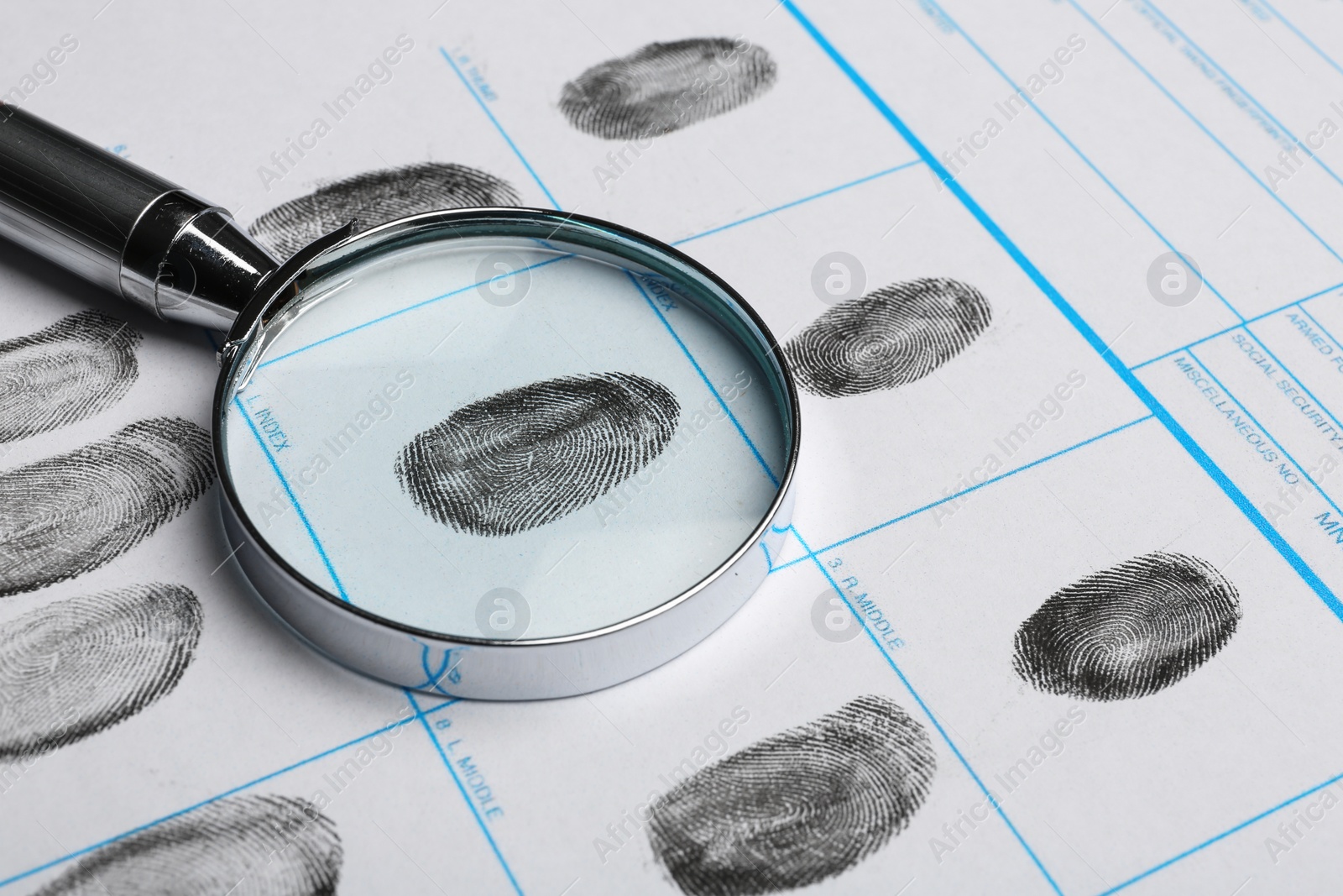 Photo of Magnifying glass and criminal fingerprint card, closeup