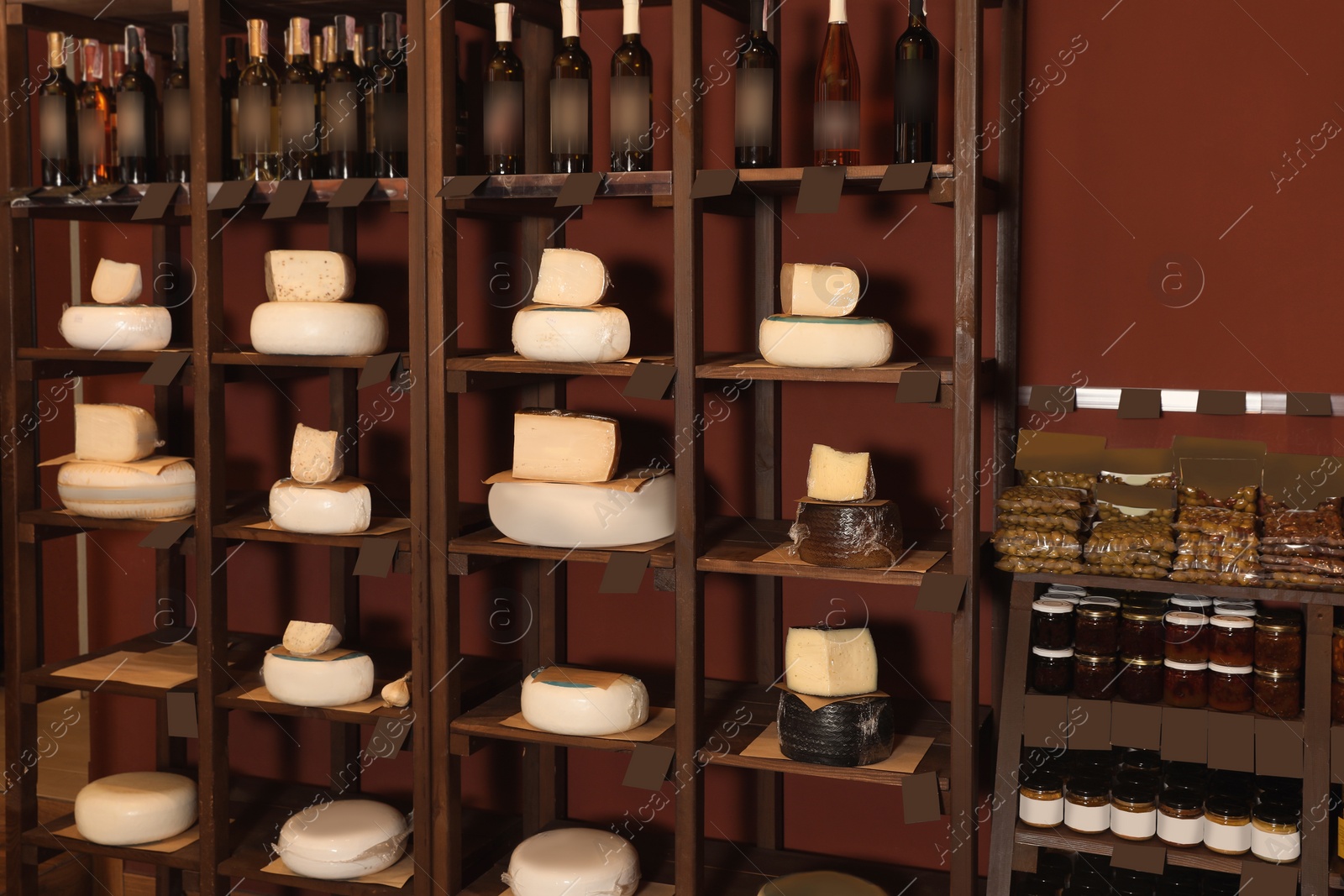 Photo of Different types of delicious cheeses and alcohol drinks on rack in store