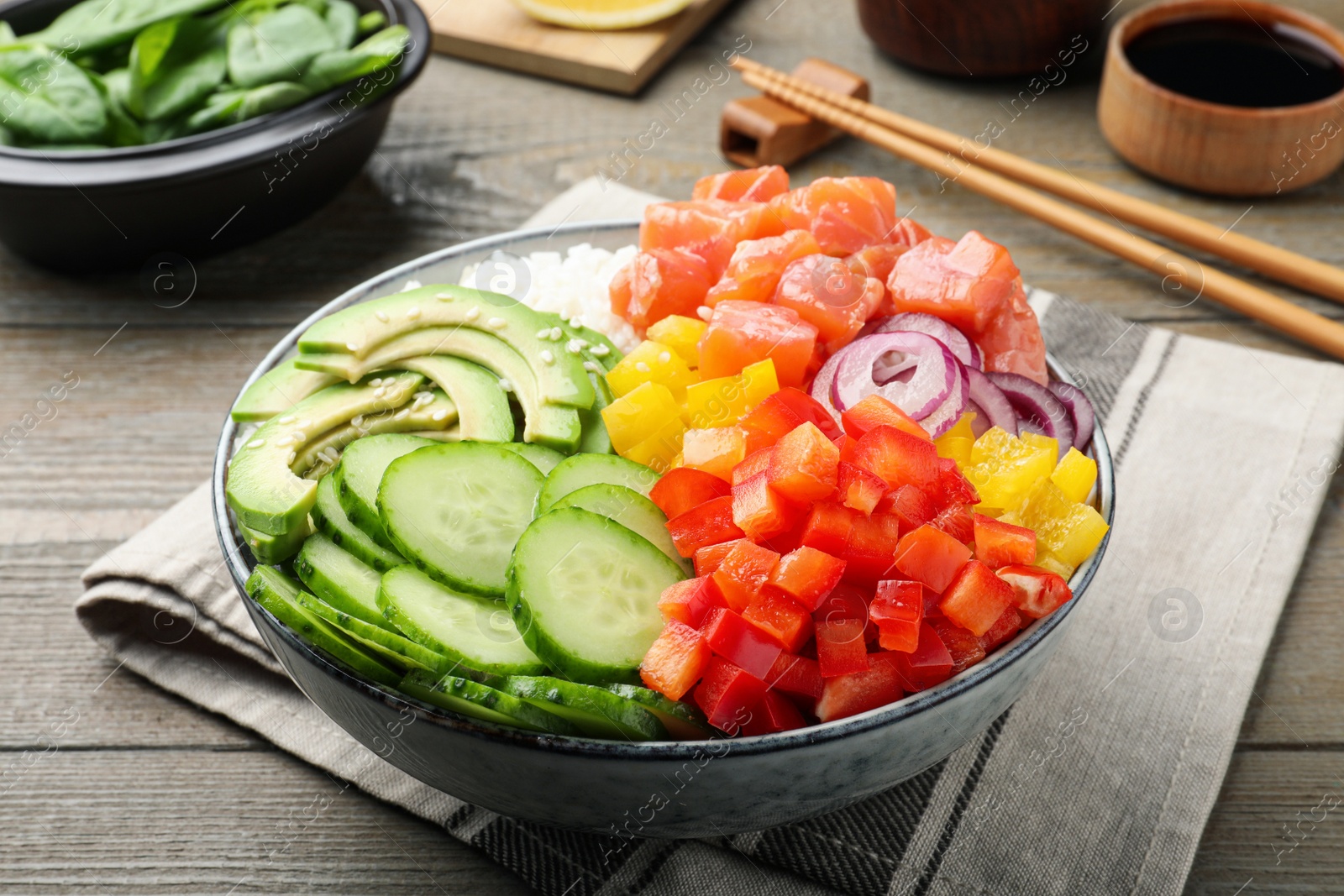 Photo of Delicious poke bowl with salmon and vegetables served on wooden table, closeup