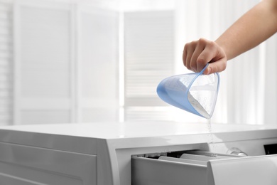 Photo of Woman pouring powder into drawer of washing machine indoors, closeup with space for text. Laundry day