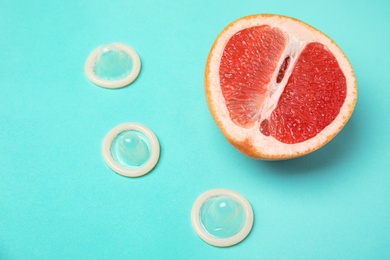 Half of grapefruit and condoms on turquoise background, above view. Sex concept