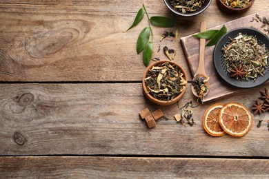 Flat lay composition with different dry teas on wooden table, space for text