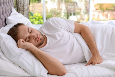 Young handsome man sleeping in bed at home. Early morning