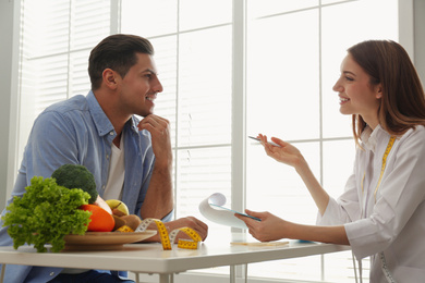 Photo of Young nutritionist consulting patient at table in clinic