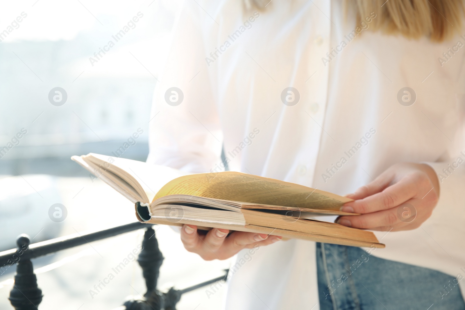 Photo of Woman reading book outdoors on sunny day, closeup
