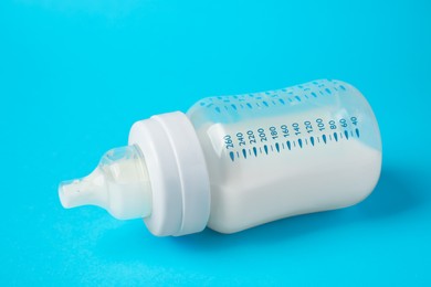 One feeding bottle with milk on light blue background, closeup