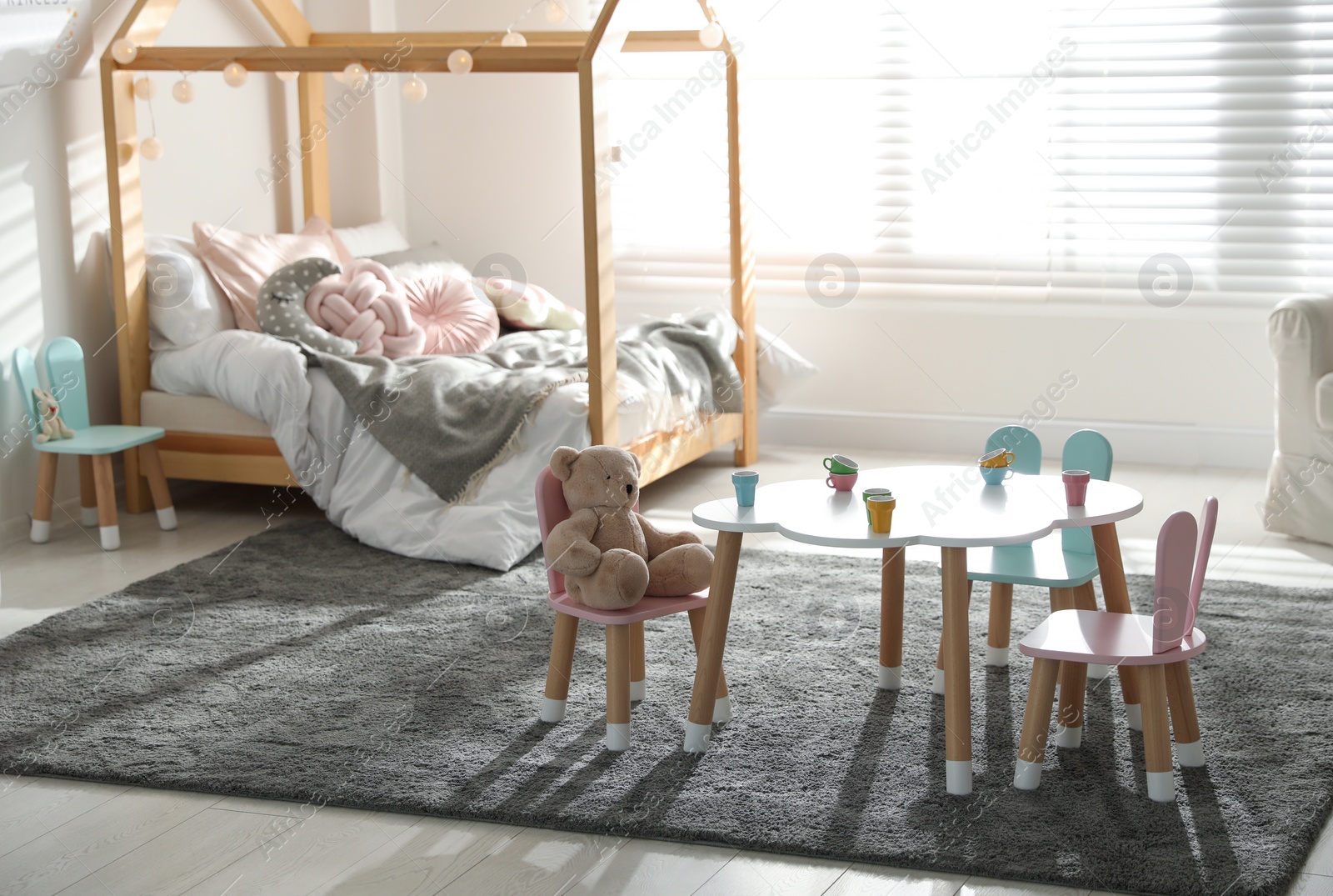 Photo of Small table and chairs with bunny ears in children's bedroom interior