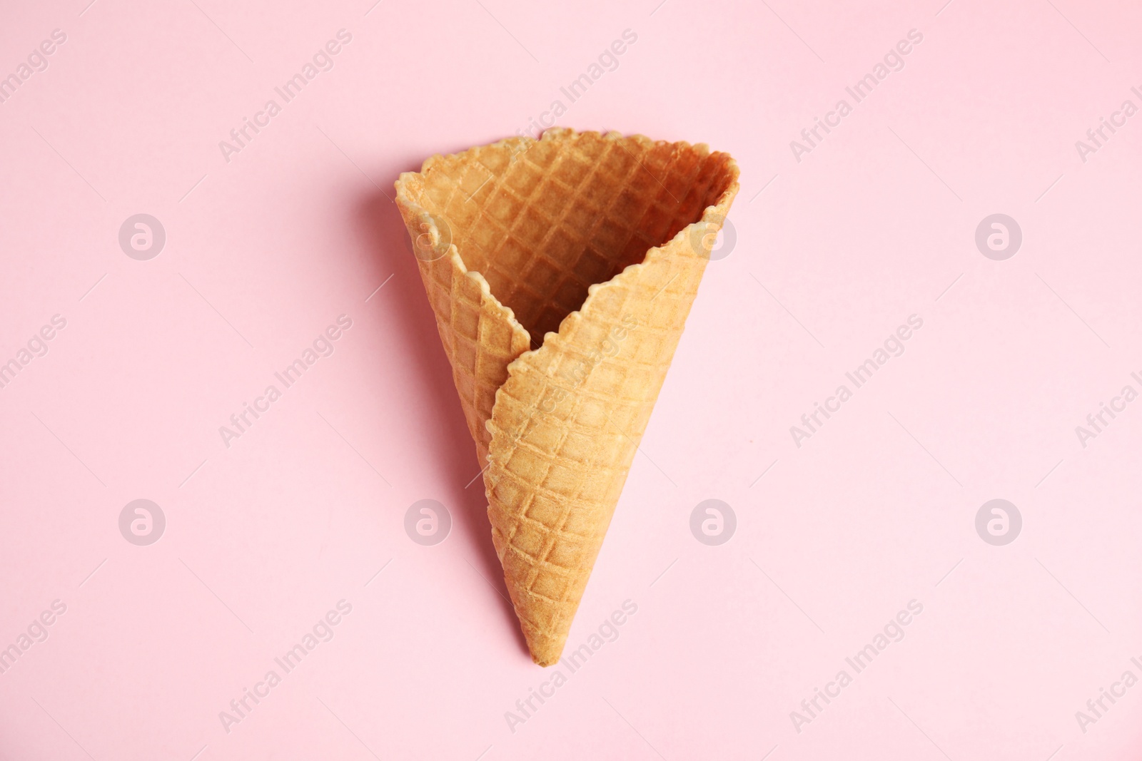 Photo of Empty wafer ice cream cone on pink background, top view