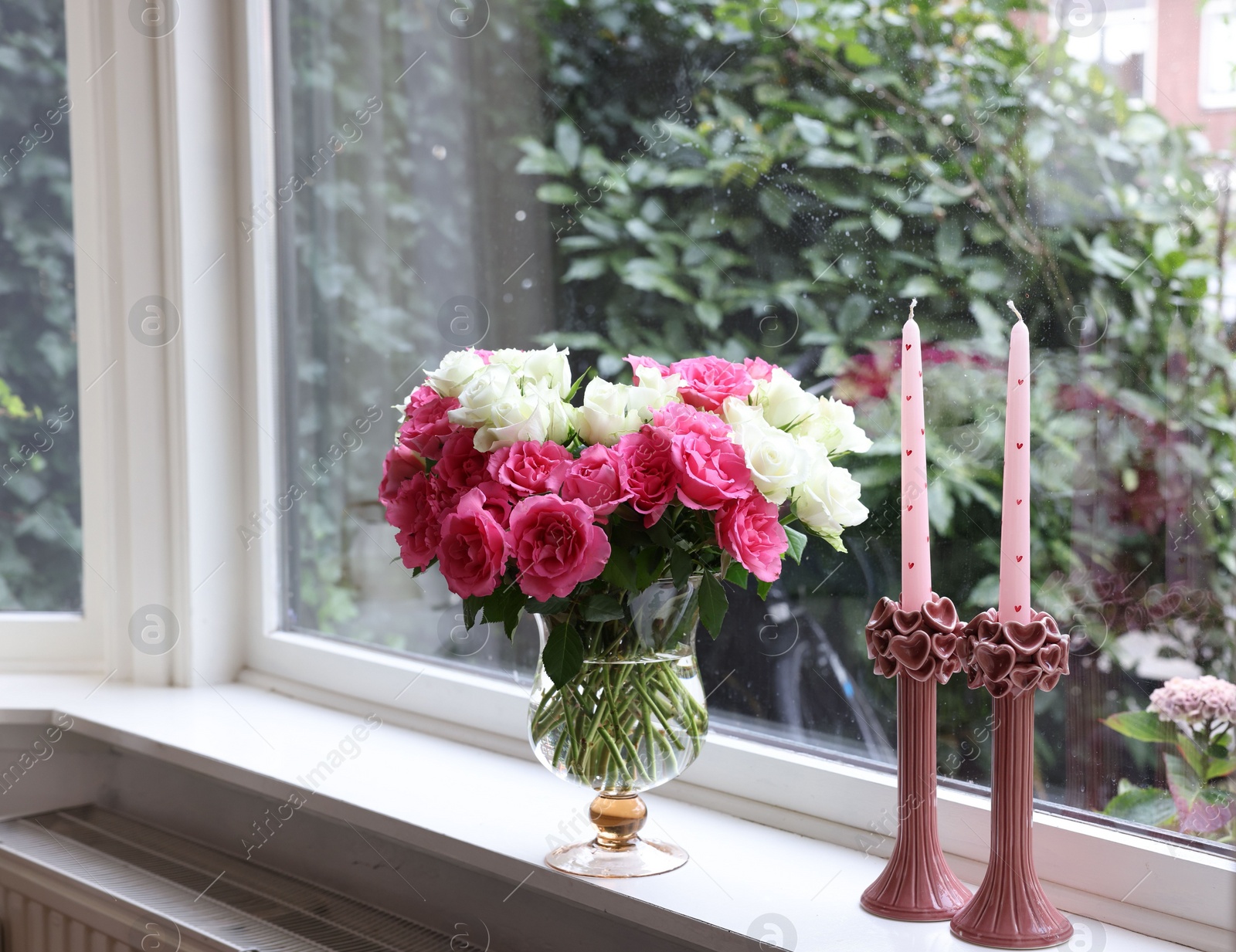 Photo of Vase with beautiful bouquet of roses and candles on windowsill indoors, space for text