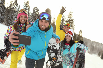 Photo of Group of friends taking selfie on snowy hill. Winter vacation