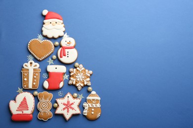 Christmas tree shape made of delicious gingerbread cookies on blue background, flat lay. Space for text