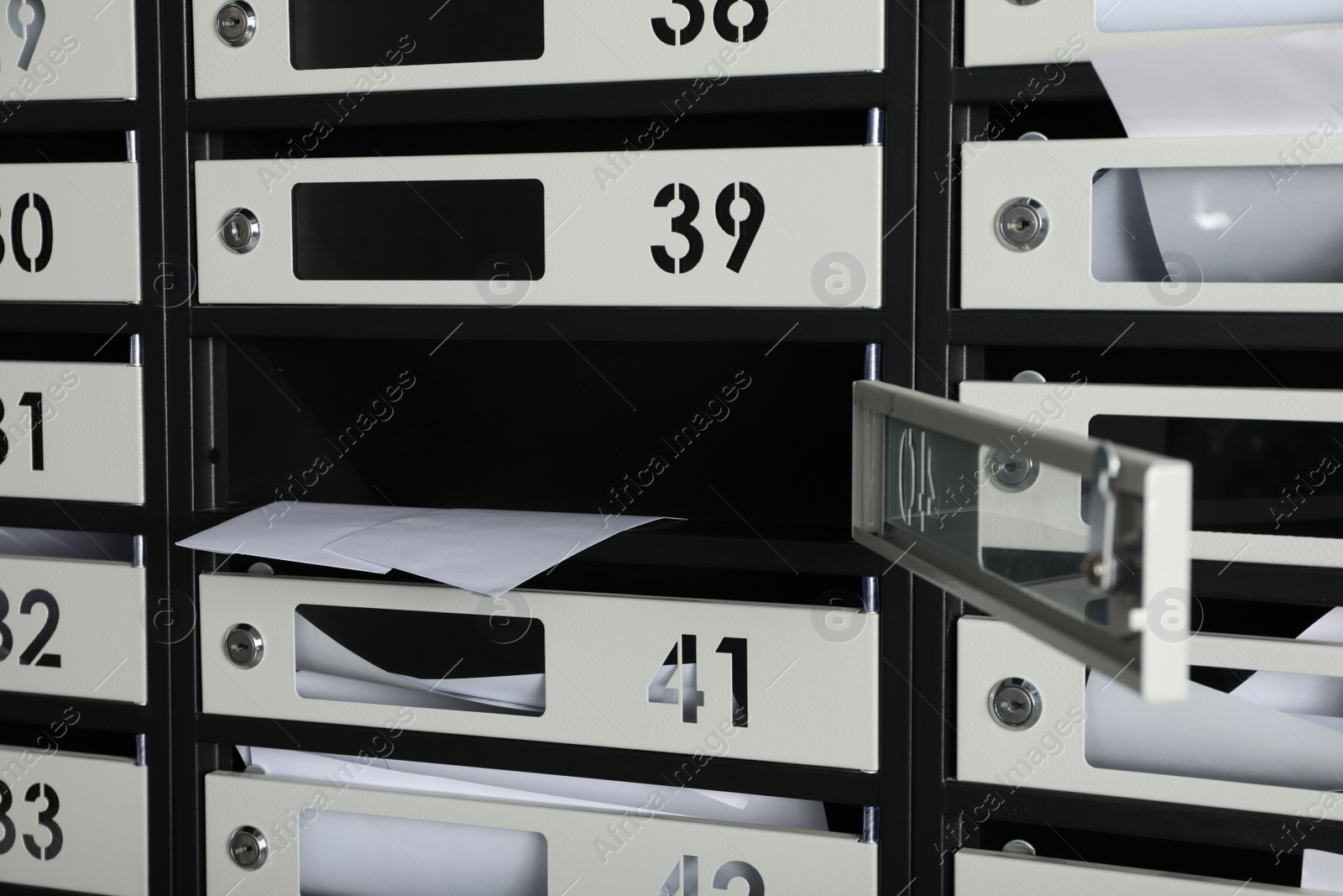 Photo of Open mailbox with keyhole, number and receipts, closeup