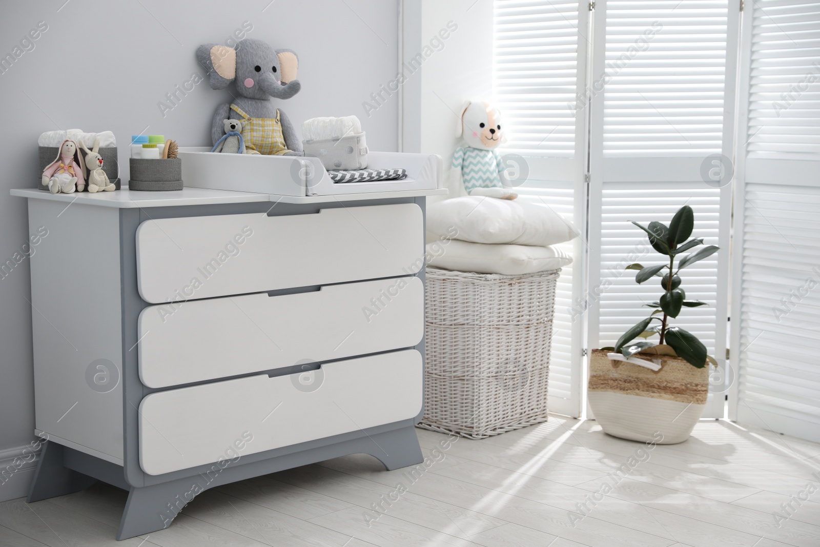 Photo of Changing tray and pad on chest of drawers in baby room. Interior design