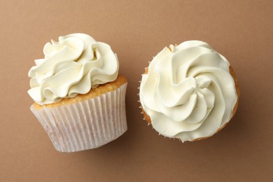 Tasty vanilla cupcakes with cream on dark beige background, top view