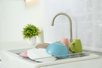 Photo of Drying rack with clean dishes over sink in kitchen