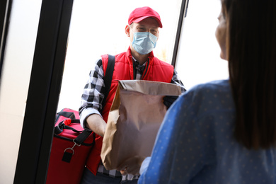 Photo of Courier giving order to woman at entrance. Delivery service during coronavirus quarantine