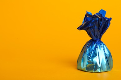 Candy in blue wrapper on yellow background. Space for text