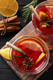 Photo of Aromatic punch drink and ingredients on black wooden table, flat lay