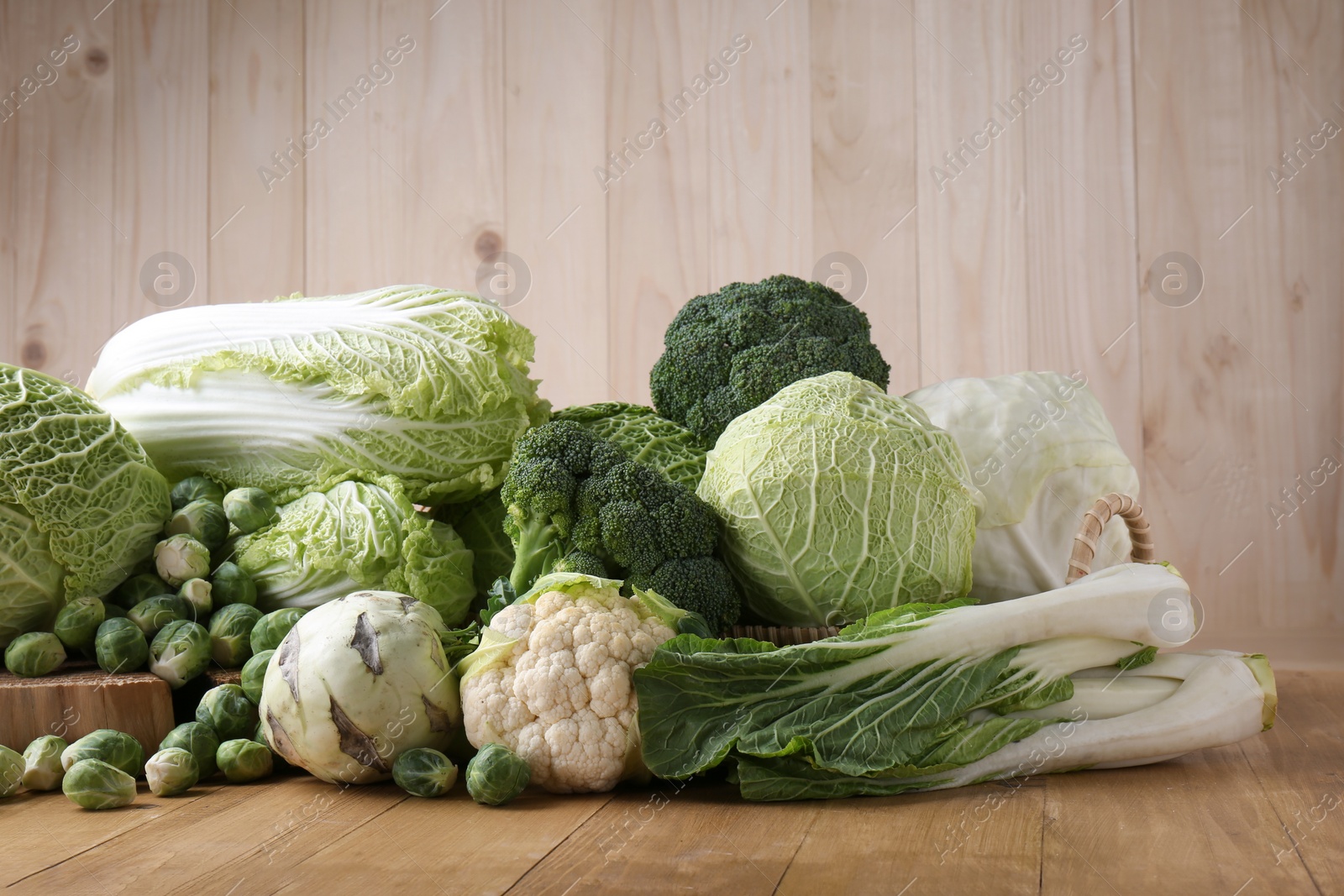 Photo of Many different types of fresh cabbage on wooden table