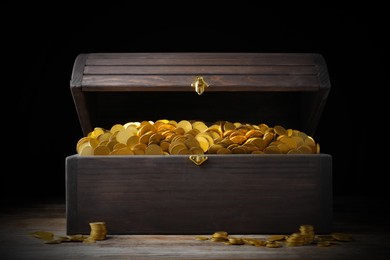 Image of Open treasure chest with gold coins on wooden table