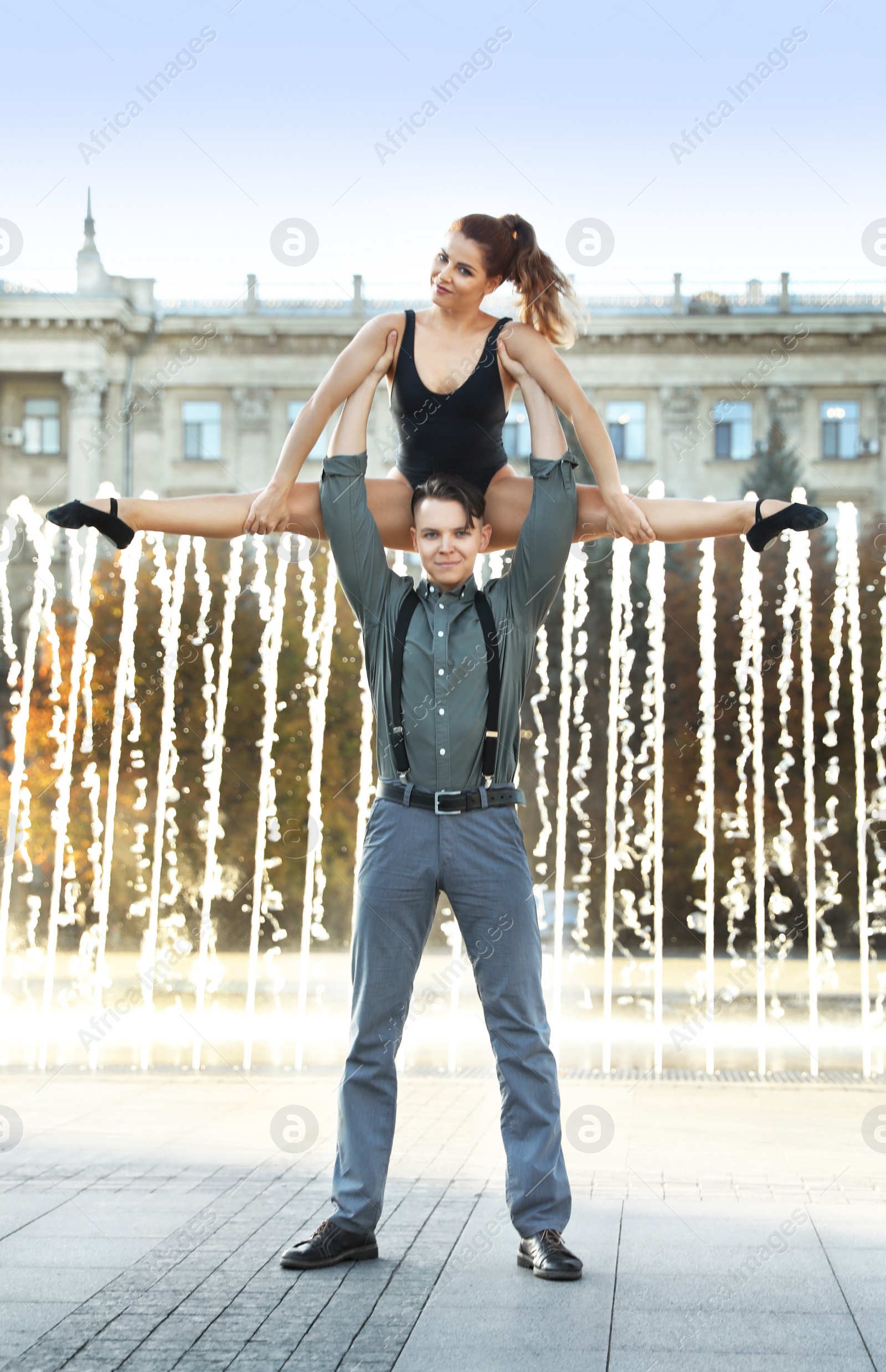 Photo of Beautiful young couple practicing dance moves near fountain outdoors