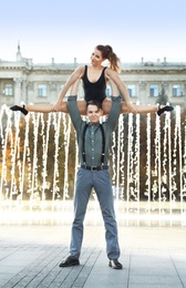 Beautiful young couple practicing dance moves near fountain outdoors