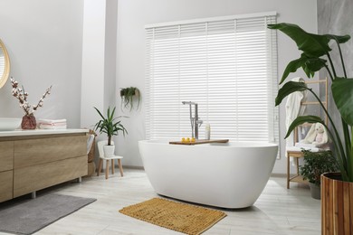 Stylish bathroom interior with beautiful tub and decor elements