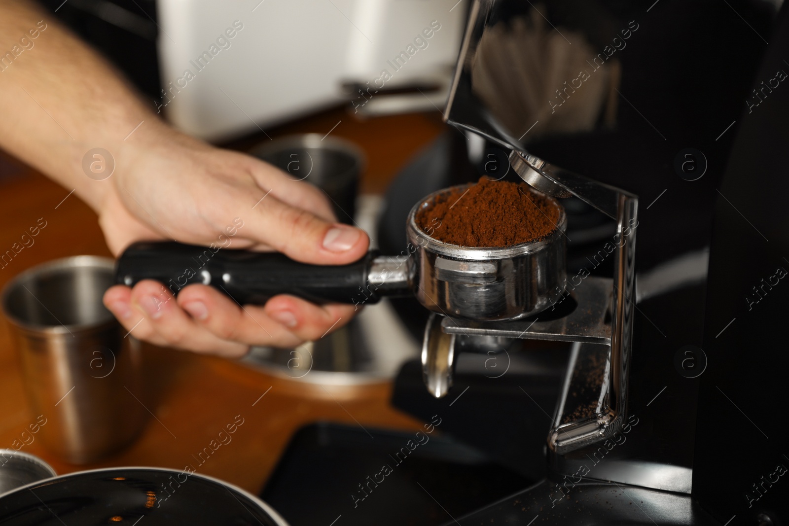 Photo of Barista pouring milled coffee from grinding machine into portafilter, closeup