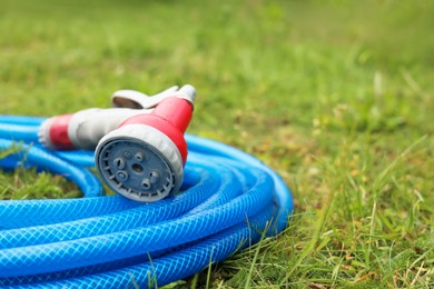 Watering hose with sprinkler on green grass outdoors, closeup. Space for text