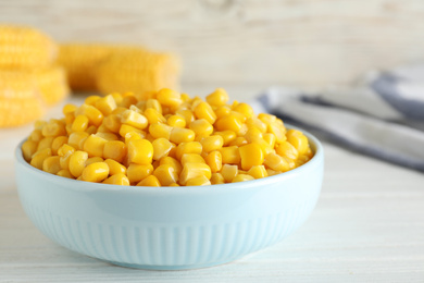 Photo of Delicious canned corn in bowl on white wooden table, closeup