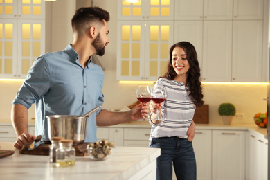 Photo of Lovely young couple drinking wine while cooking together at kitchen