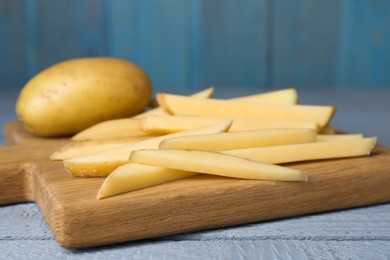 Photo of Whole and cut potatoes on grey wooden table, closeup. Cooking delicious french fries