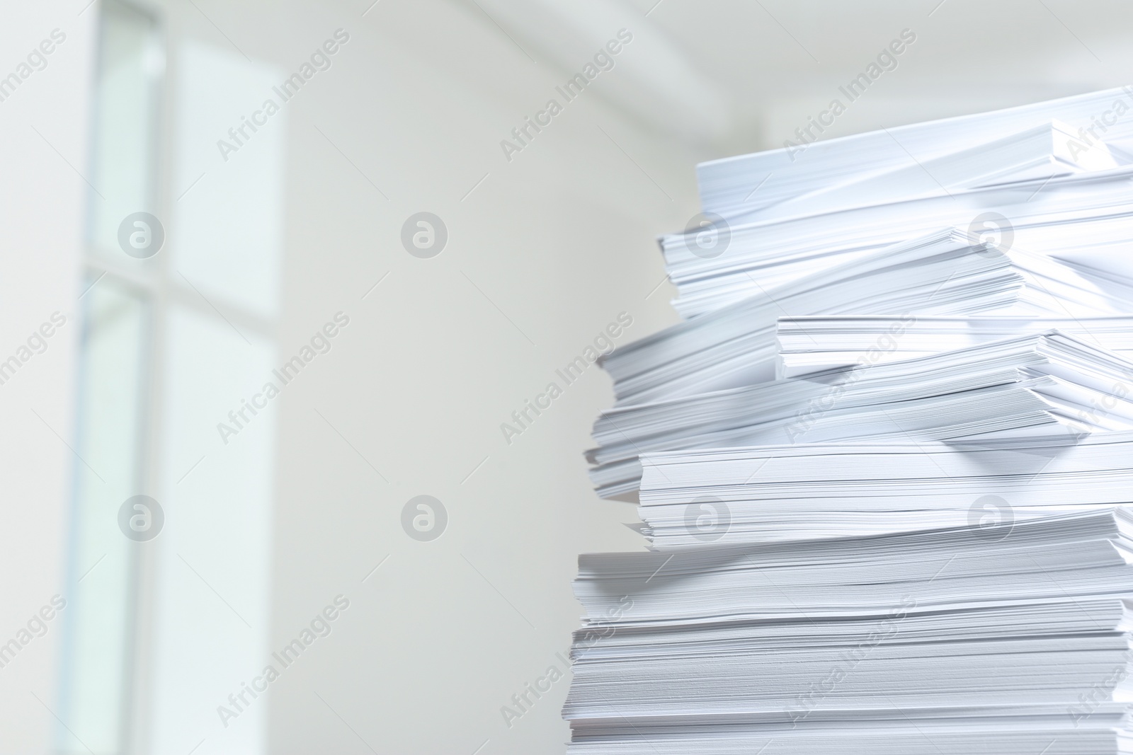 Photo of Stack of paper sheets against blurred background, closeup. Space for text