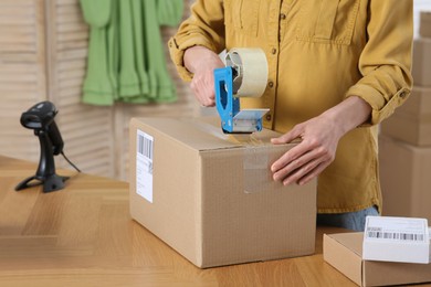 Photo of Seller taping parcel at workplace, closeup. Online store