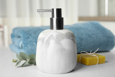 Marble dispenser, eucalyptus and soap bar on white table