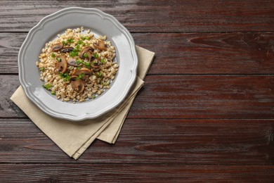 Photo of Delicious pearl barley with onion and mushrooms on wooden table, top view. Space for text