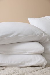 Soft white pillows near beige wall indoors