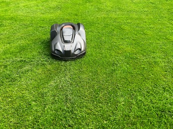 Modern robot lawn mower on green grass in garden