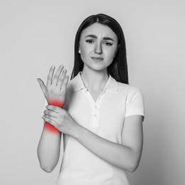 Woman suffering from rheumatism on light background. Black and white effect with red accent in painful area