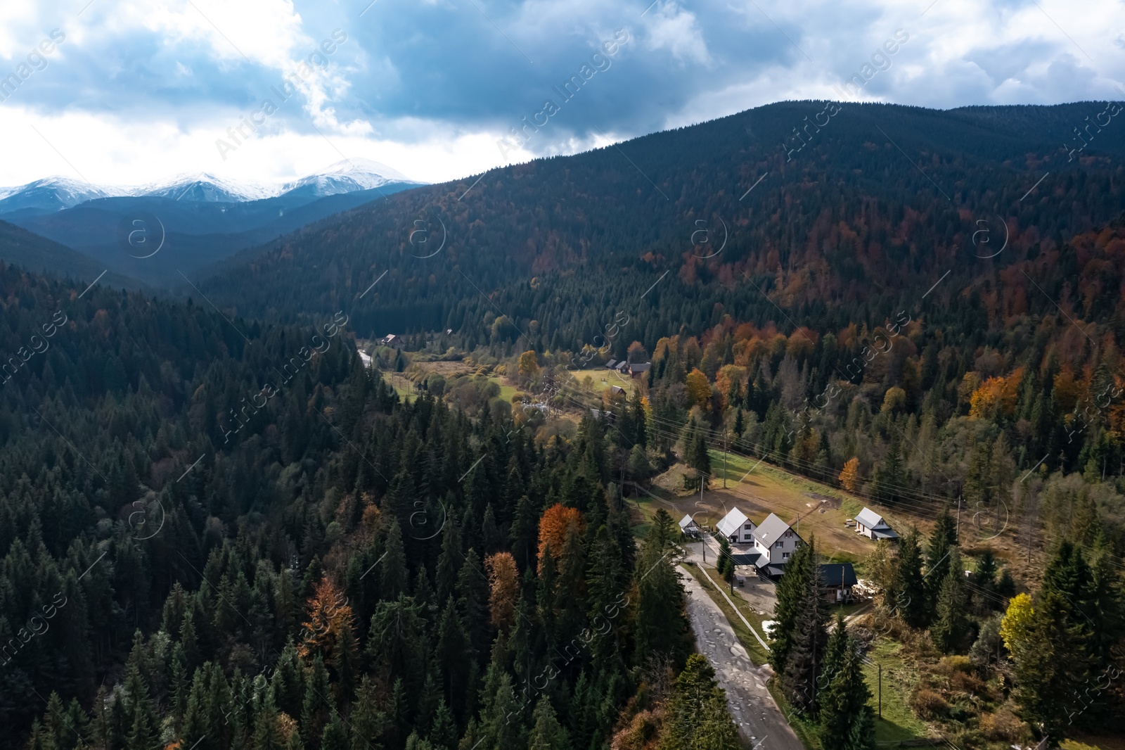 Image of Aerial view of beautiful forest, road and mountain village on autumn day