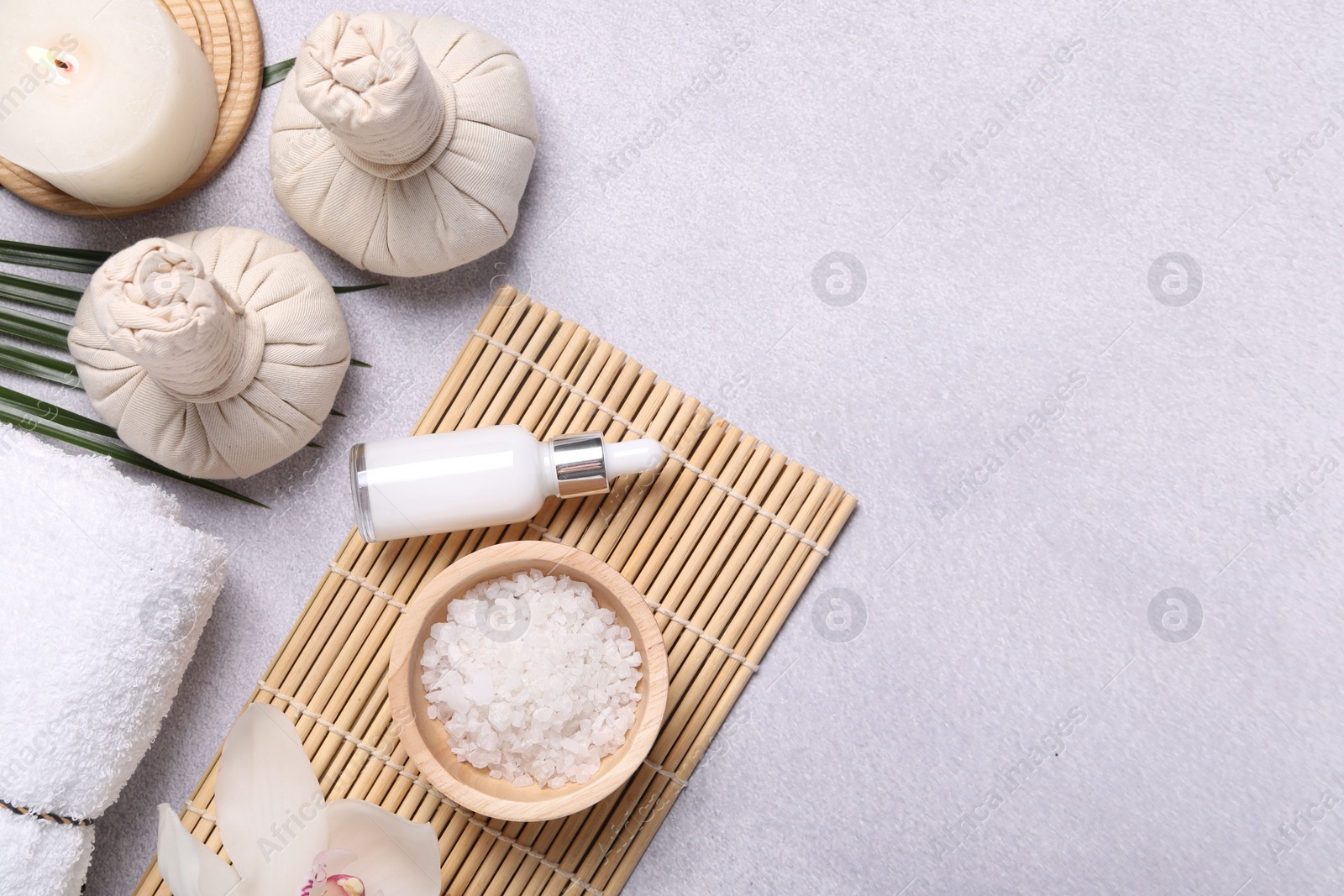 Photo of Flat lay composition with herbal massage bags, spa products and leaves on light grey table. Space for text