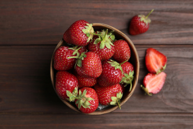 Photo of Delicious ripe strawberries in bowl on wooden table, flat lay