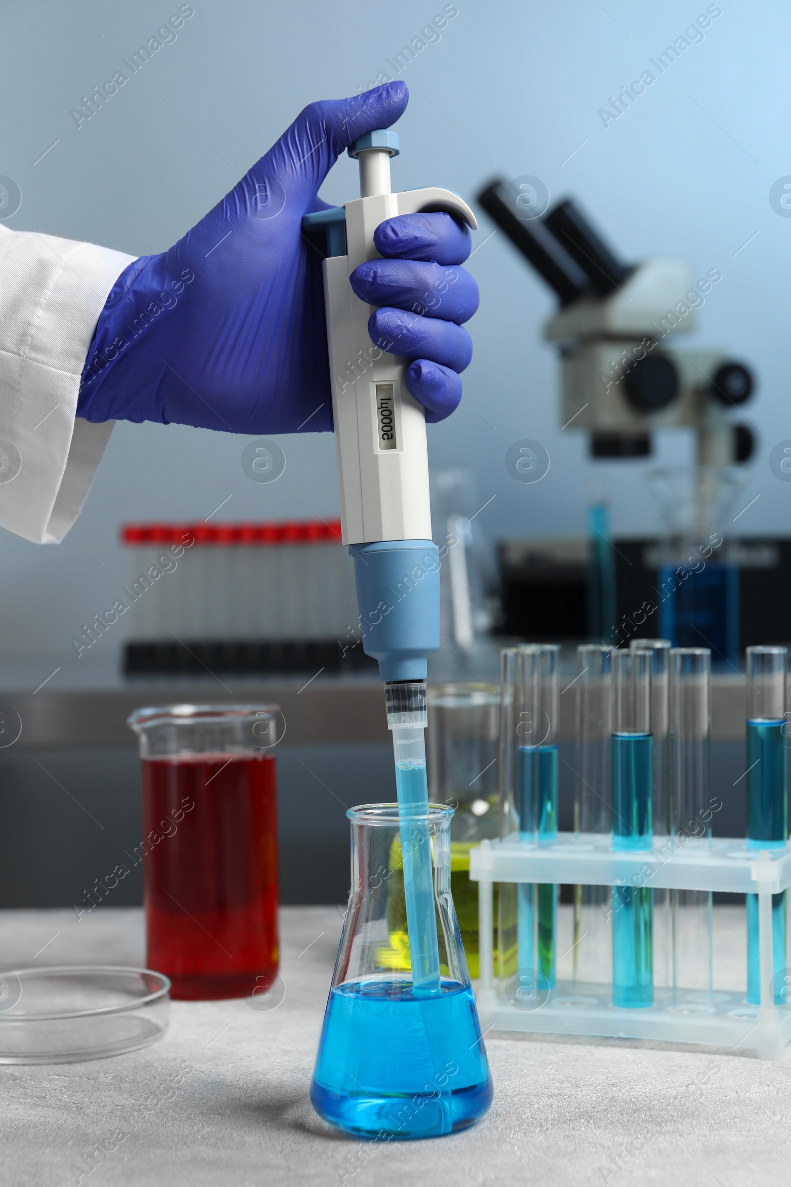 Photo of Laboratory analysis. Scientist dripping sample with micropipette into flask indoors, closeup