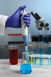 Photo of Laboratory analysis. Scientist dripping sample with micropipette into flask indoors, closeup