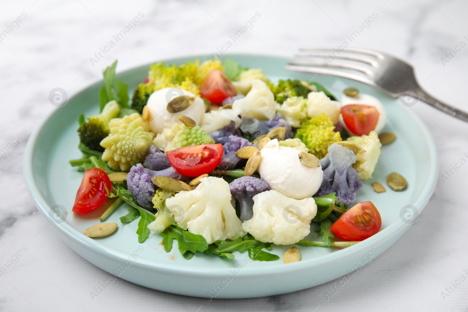 Photo of Delicious salad with cauliflower, tomato and cheese served on white marble table, closeup