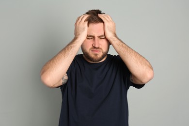 Man suffering from migraine on grey background