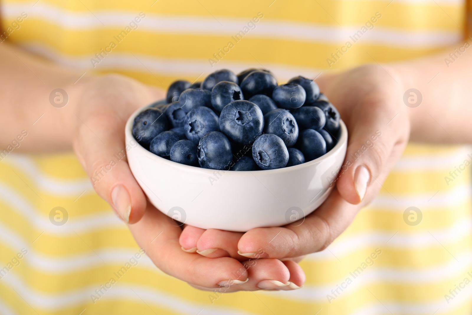 Photo of Woman holding tasty fresh blueberries, closeup view