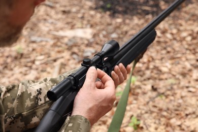 Photo of Man with hunting rifle wearing camouflage outdoors, closeup